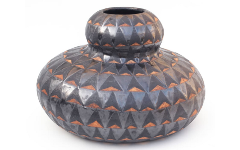 The image shows a ceramic pot created by Pilar Wiley, titled "Cornrow Gourd." The pot is bulbous and has a dark gray glaze with triangular patterns revealing a rust-colored underglaze. The artwork measures 12 x 18 x 16.5 inches and was created in 2019.